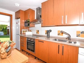 Une cuisine compacte avec des meubles en bois, un four encastré, un évier en acier inoxydable et un grille-pain.
