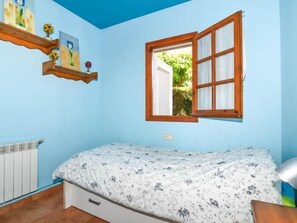 A bedroom with a bed, a window, a radiator, and a shelf with pictures. - Casa Socias - Comarruga (Comarruga)