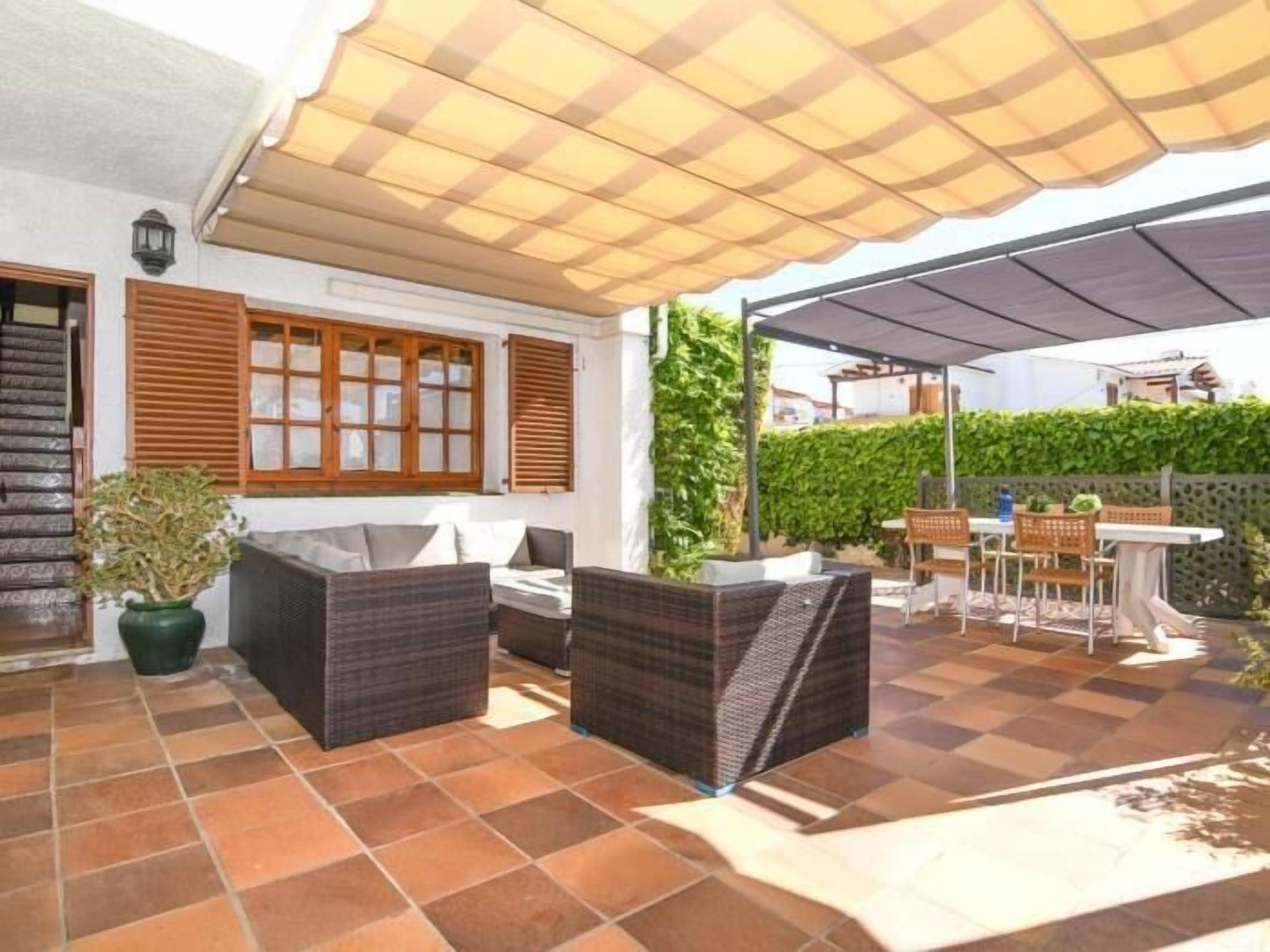 An outdoor patio with wicker furniture, a table, and a potted plant.
