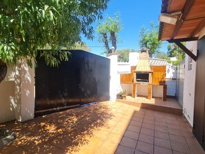 A courtyard with a black gate, a brick oven, and a tiled floor. - CORAL I - Roda de Berà (Roda de Berà)