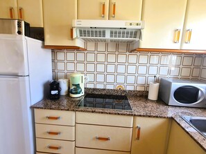 A kitchen with a refrigerator, microwave, coffee maker, and a gas stove. - CORAL I - Roda de Berà (Roda de Berà)
