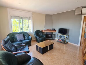 A living room with a fireplace, leather sofas, a coffee table, and a TV stand. - CORAL I - Roda de Berà (Roda de Berà)