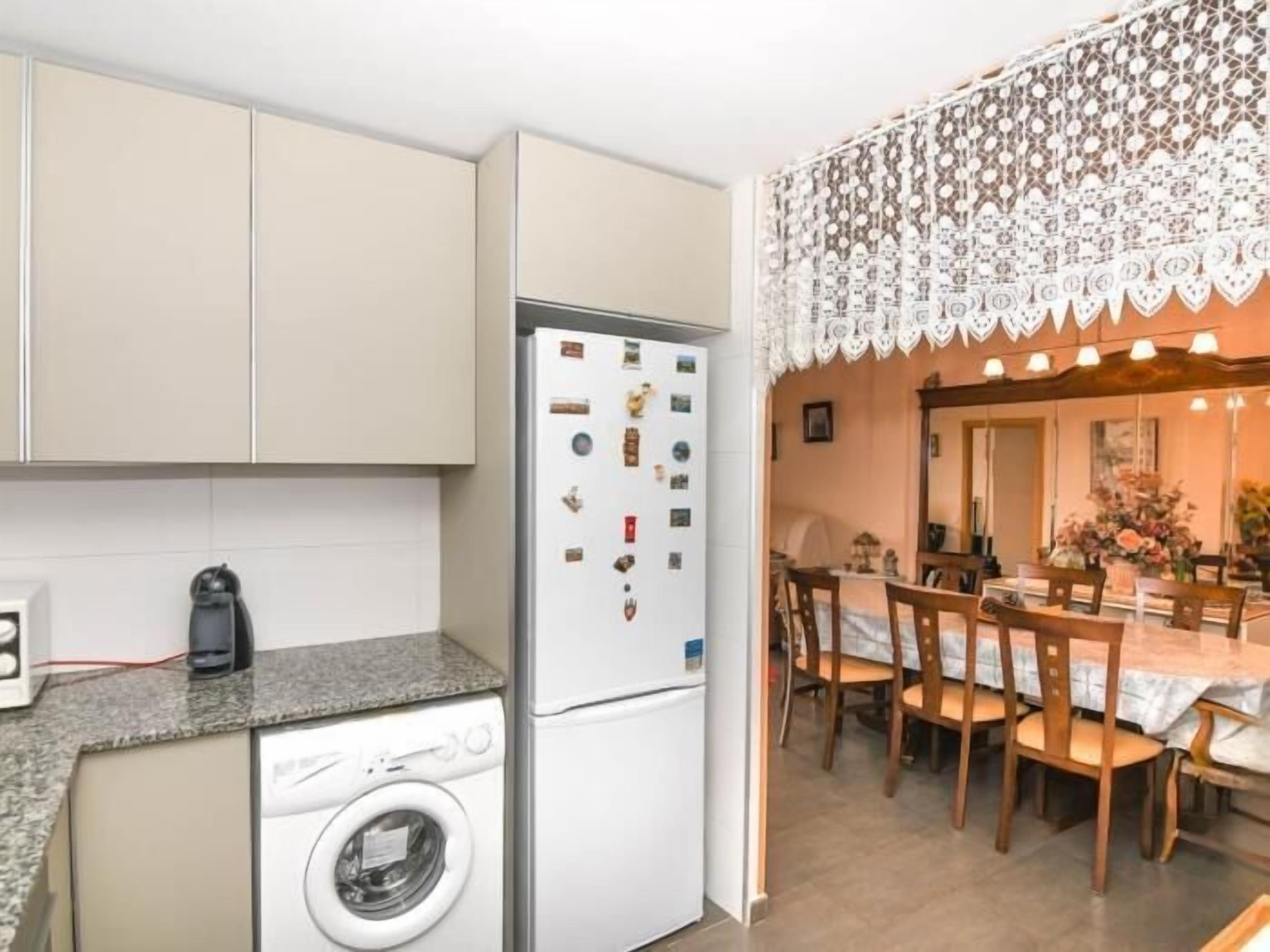 Una cocina compacta con lavadora, refrigerador y comedor con mesa y sillas.
