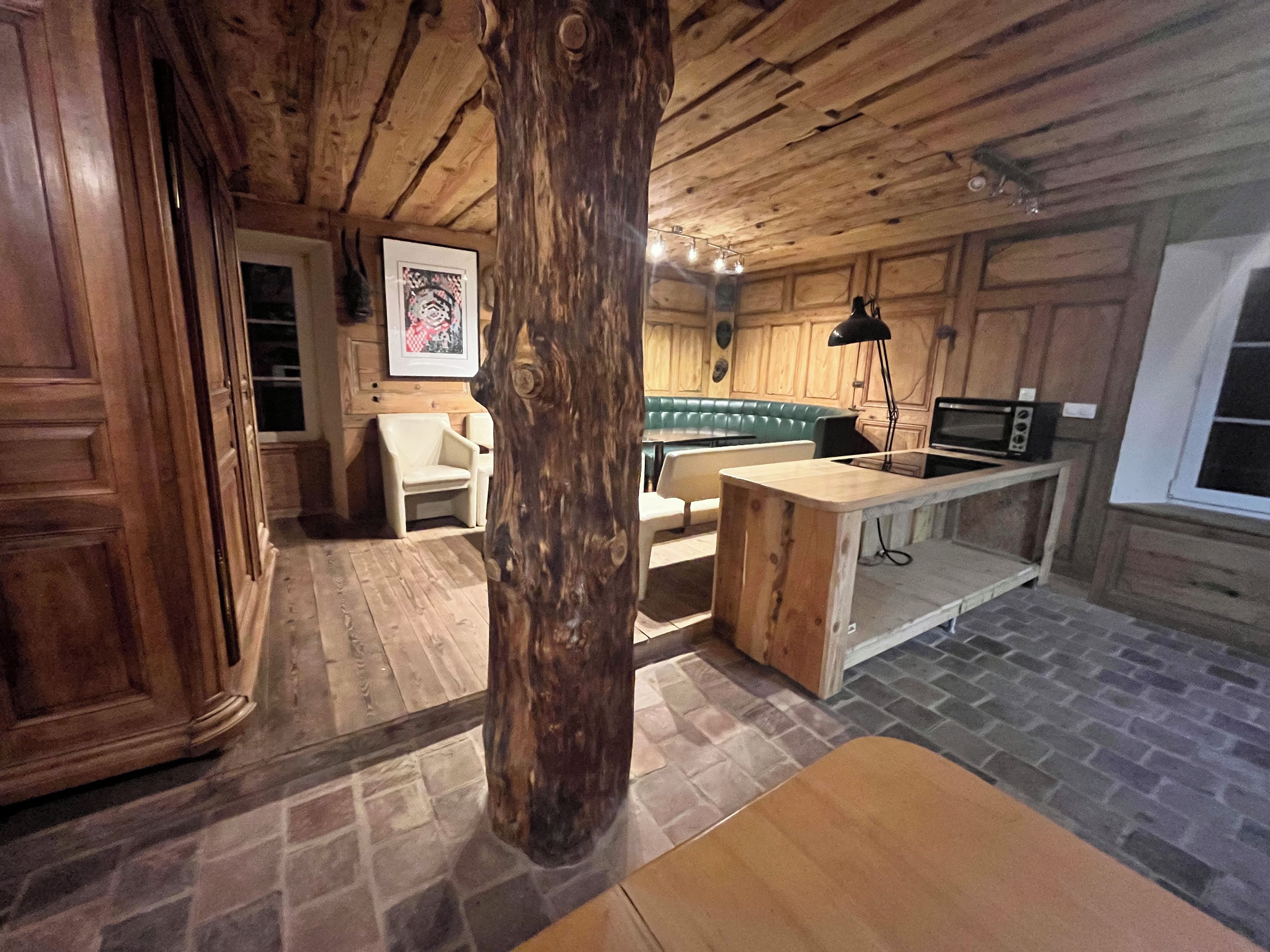 Un interior rústico con techo de madera, piso de piedra, kitchenette y una zona de estar.