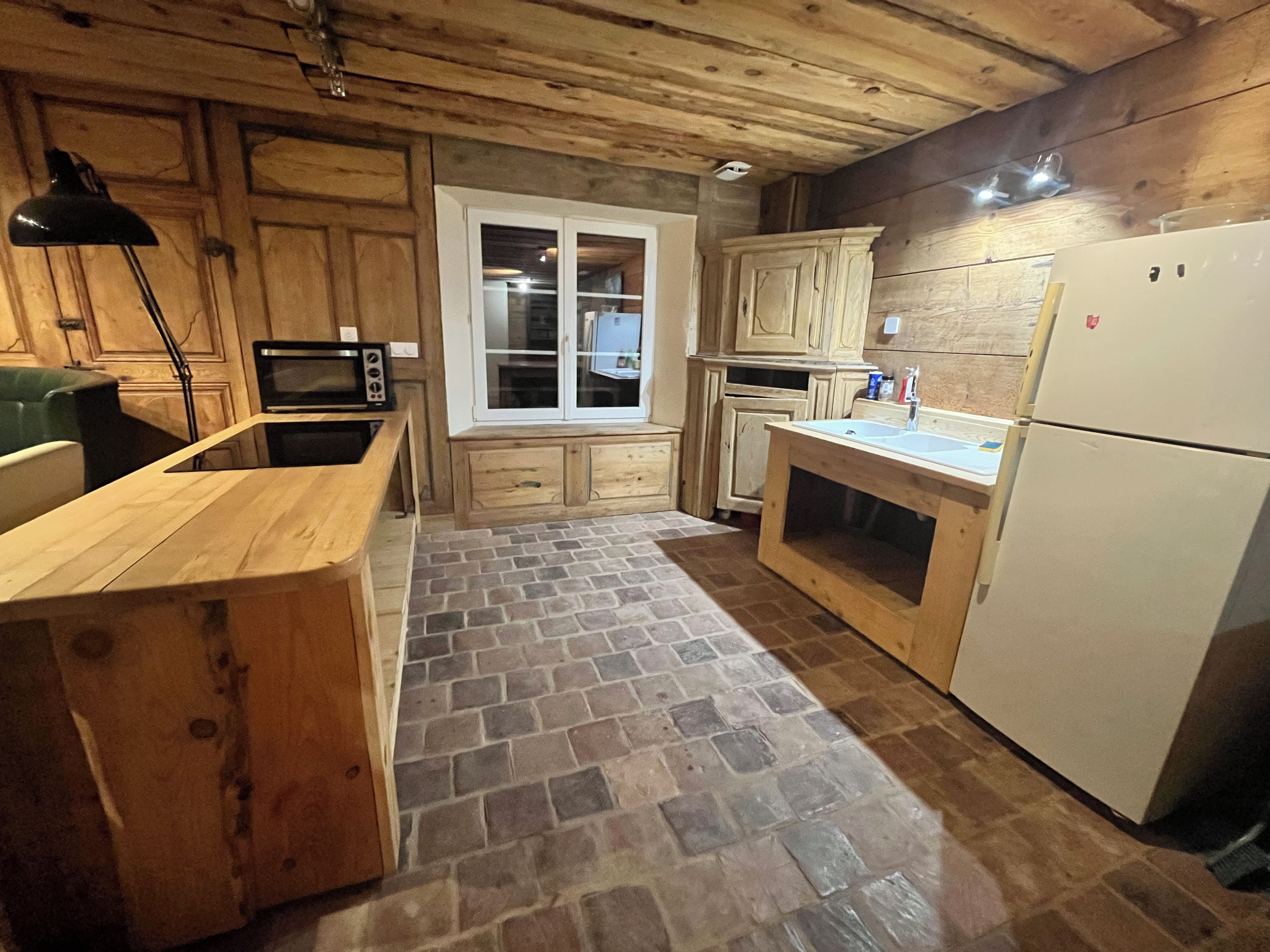 Una cocina con armarios de madera, microondas, refrigerador y ventana.
