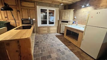 Una cocina con armarios de madera, microondas, refrigerador y ventana.