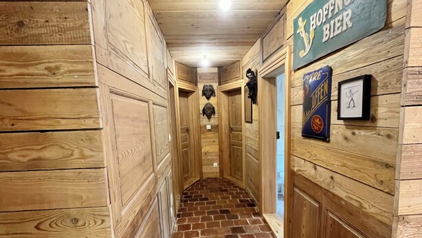 Un pasillo de madera con piso de ladrillo, paredes de madera y un letrero que dice 'HOFFENUNG BIER'.
