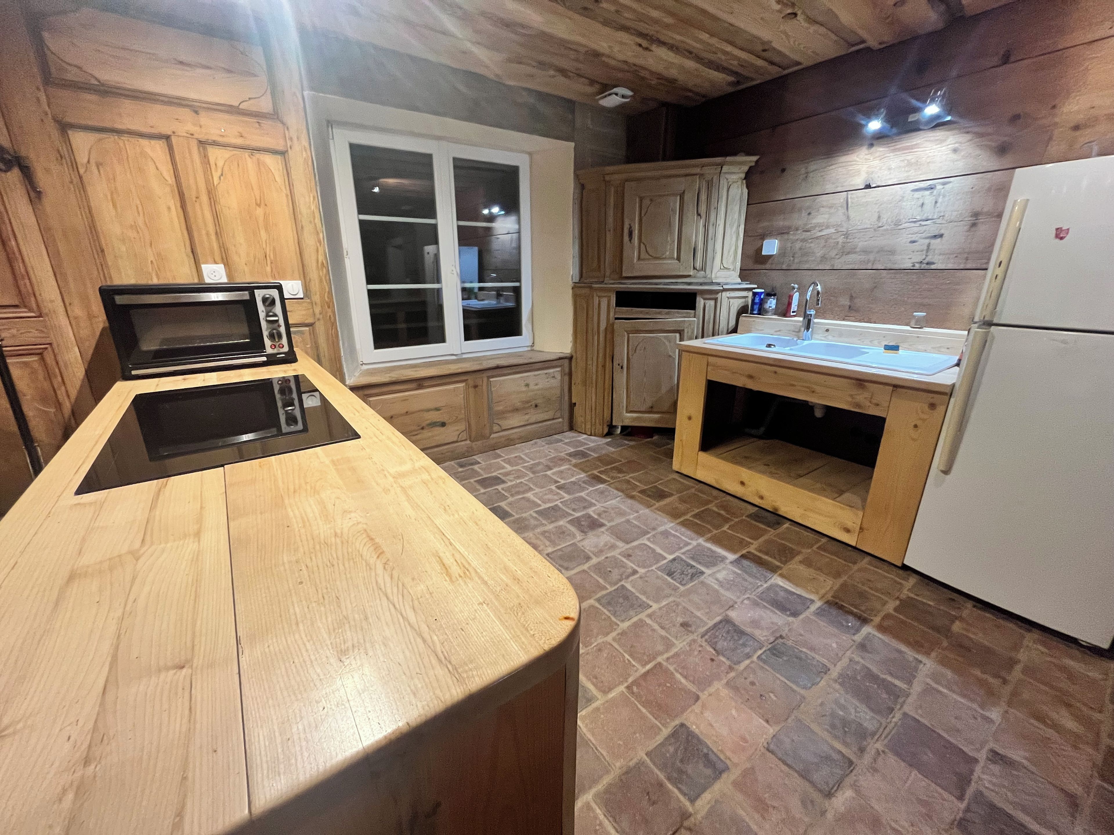 Una cocina con encimera de madera, horno empotrado, lavaplatos y refrigerador.