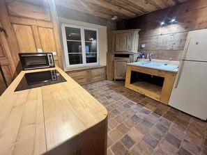 A kitchen with a wooden countertop, a built-in oven, a sink, and a refrigerator.