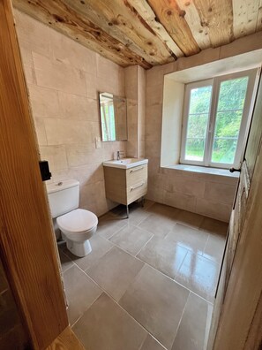 A bathroom with a toilet, sink, and window.