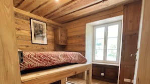Una cabaña de madera con una cama nido, un cuadro en la pared y una ventana con vistas.