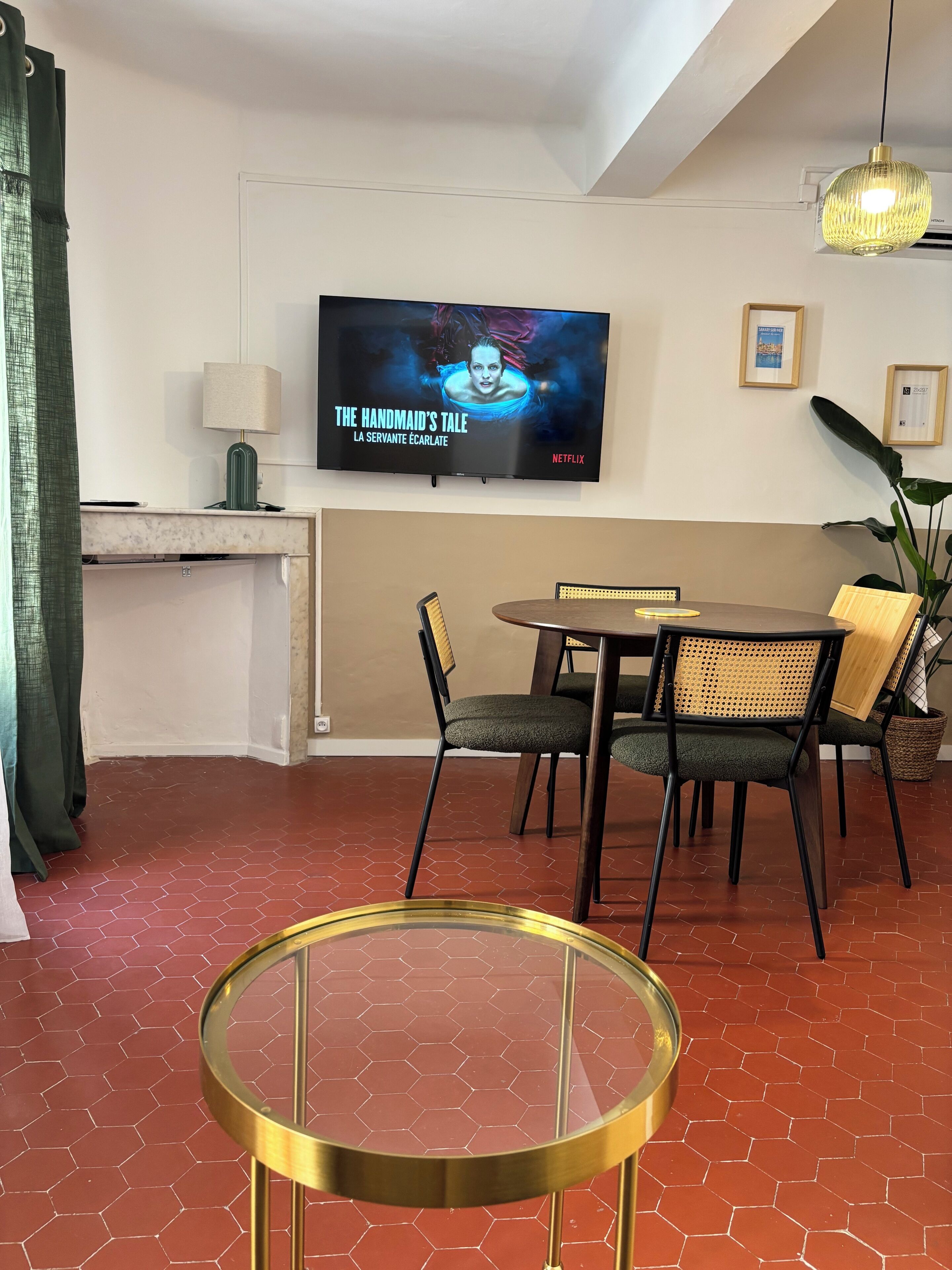 Een moderne woonkamer met een televisie, een eettafel, stoelen en een glazen salontafel.