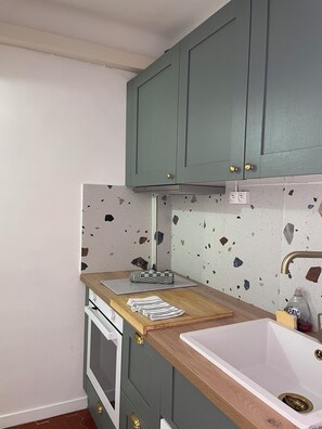 A kitchen with green cabinets, a white countertop, a sink, and a stove.