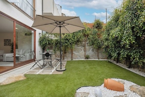 A patio with a table and chairs, a large umbrella, and a well-maintained lawn. - 1BR With Private Patio Porto Urban Flats (Porto)