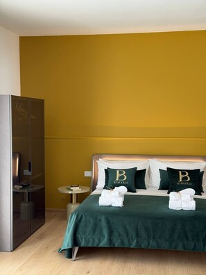 A hotel room with a bed, two pillows with a logo, a bedside table, and a wardrobe. - In the heart of Salento, suites with private hot tubs (Cutrofiano)