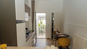 A modern kitchen with a dining area, a table with chairs, and a view to an outdoor patio. - In the heart of Salento, suites with private hot tubs (Cutrofiano)