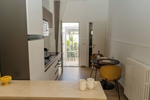 A modern kitchen with a dining area, a table with chairs, and a view to an outdoor patio. - In the heart of Salento, suites with private hot tubs (Cutrofiano)