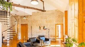 Un área de estar amplia con una pared de piedra, una escalera y un sofá moderno.