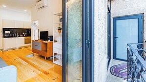 Un intérieur moderne avec une cuisine, un plancher en bois, une porte en verre et une porte bleue.