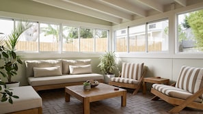 Ein Wintergarten mit einer Couch, Sesseln, einem Couchtisch und Topfpflanzen.