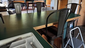 Un interior de madera con una mesa de comedor, sillas, una pequeña cocina y un televisor.