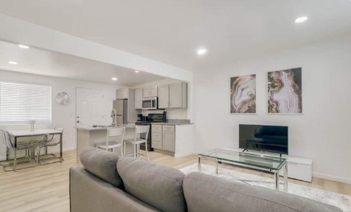 A modern living room with a sofa, a glass coffee table, and a flat-screen TV.