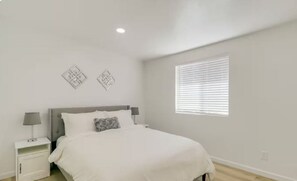 A bedroom with a bed, nightstands, a window, and wall art. - 2-bedroom townhome in beautiful Tucson! (Tucson)