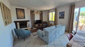 Ein Wohnzimmer mit Kamin, einer Couch, einem Fernseher und einem Essbereich.