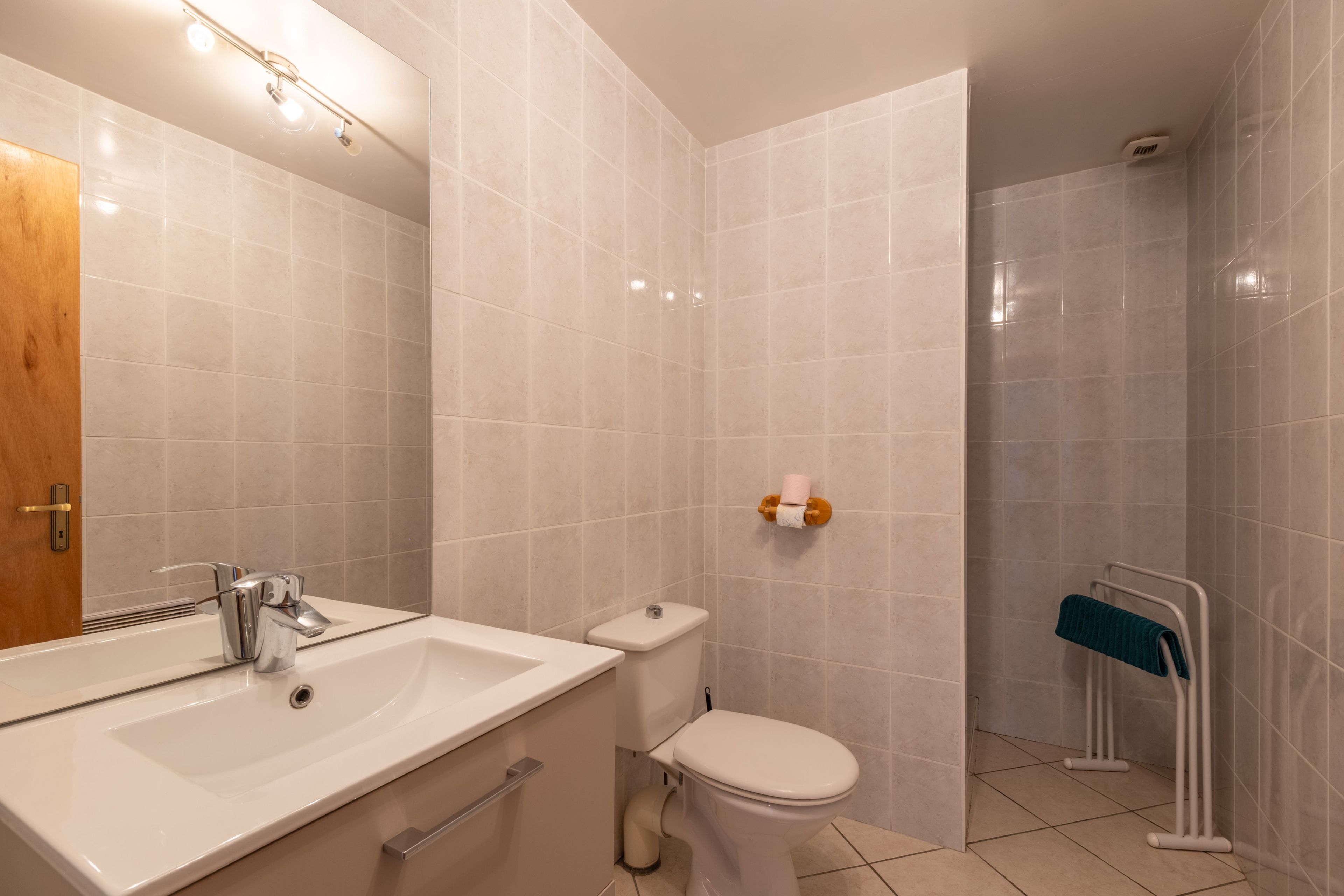 Een badkamer met een wit wastafelmeubel, toilet en douche.