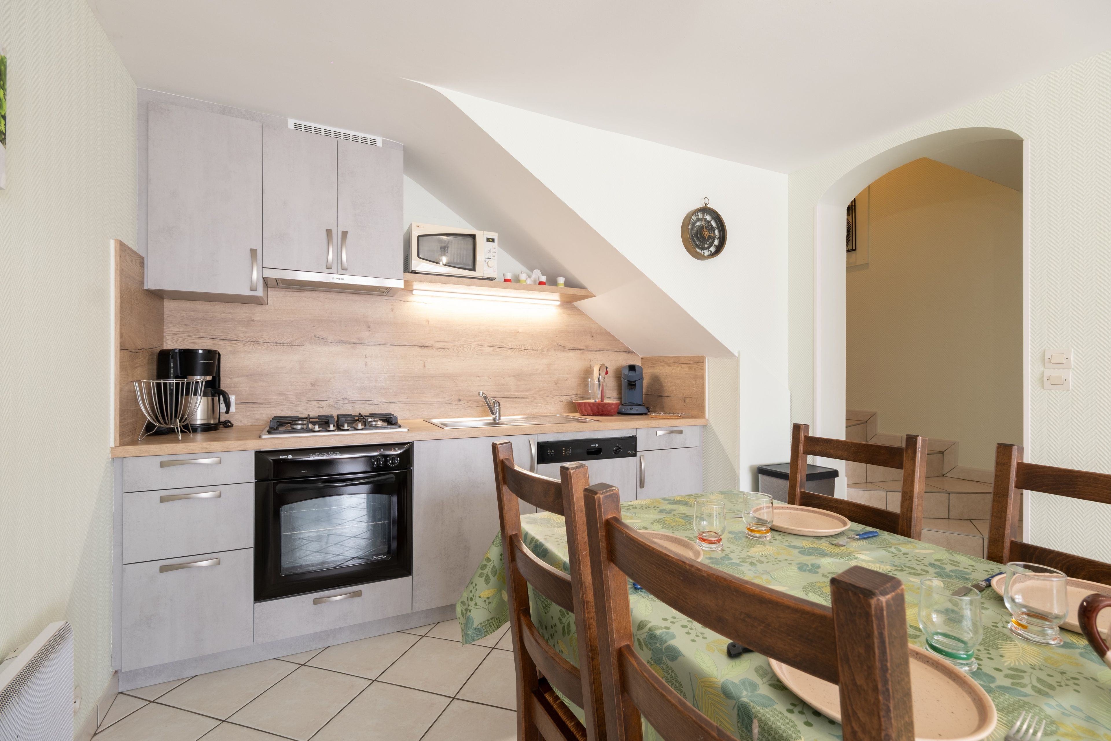 A compact kitchen with a microwave, stove, and dishwasher. There is a dining area with a table and chairs.
