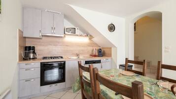 A compact kitchen with a microwave, stove, and dishwasher. There is a dining area with a table and chairs.
