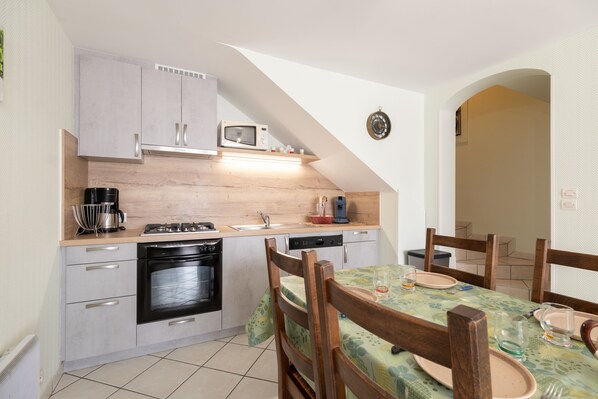 A compact kitchen with a microwave, stove, and dishwasher. There is a dining area with a table and chairs.