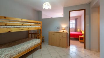 A room with bunk beds, a wooden cabinet, a desk, and a lamp.