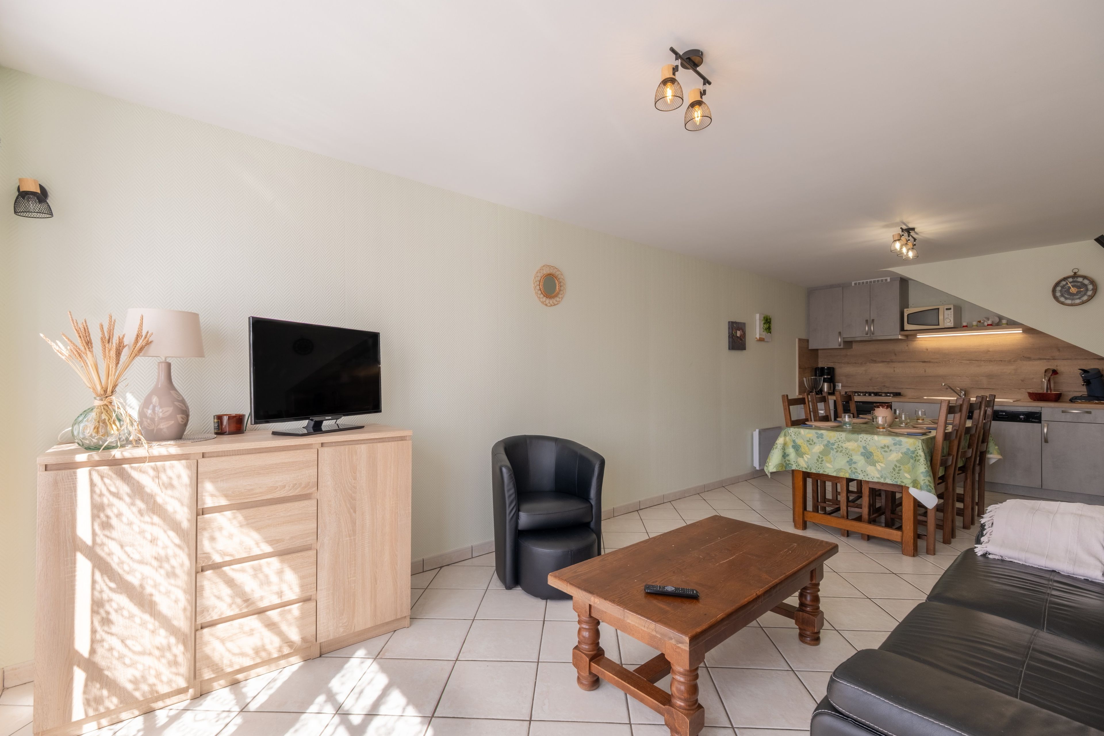 A living room with a television, a sofa, a coffee table, and a dining area with a table and chairs.