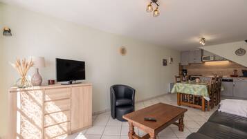 A living room with a television, a sofa, a coffee table, and a dining area with a table and chairs.