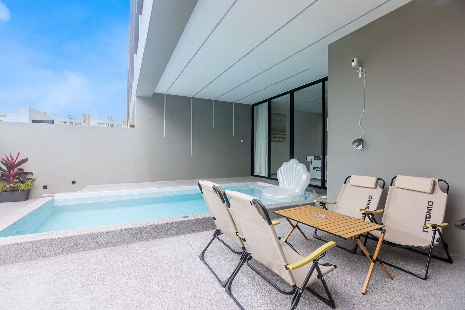 A rooftop pool area with a hot tub, two lounge chairs, and a table.