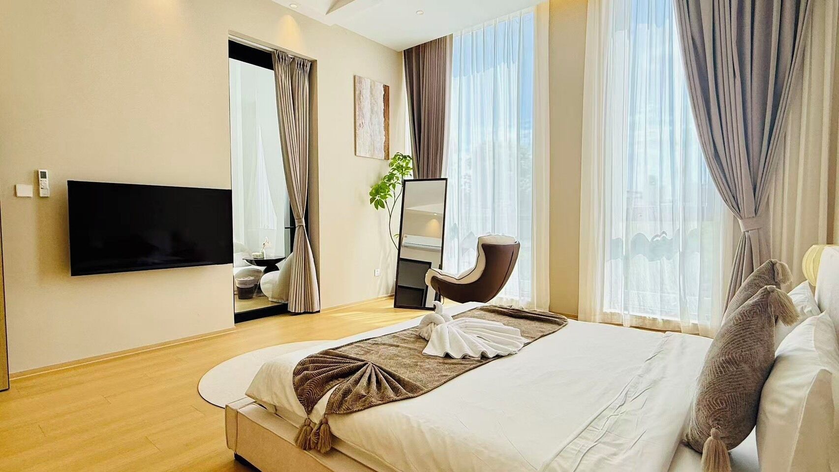Une chambre d’hôtel équipée d’un lit, d’un téléviseur à écran plat, d’une chaise, d’un miroir et d’une fenêtre avec des rideaux.
