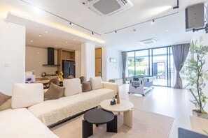 A modern living room with a sofa, a coffee table, and a pool table. - The White Heaven (Banglamung)