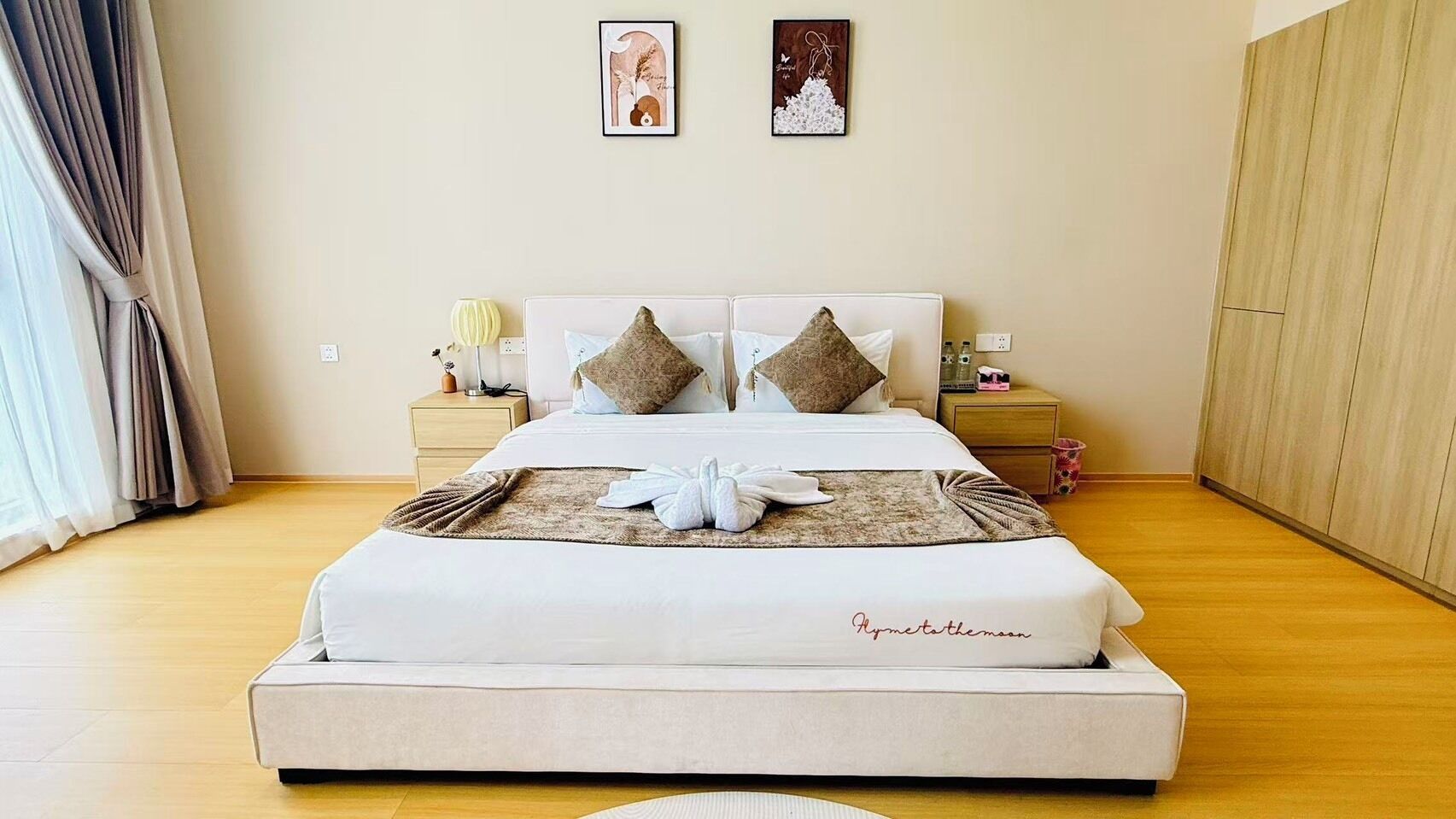 A neatly made bed with a white mattress and a blanket, a bedside table with a lamp, and two wall art pieces.