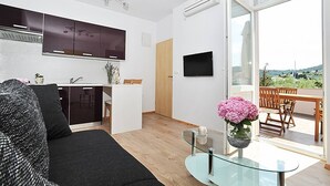 Ein moderner Wohnraum mit Küche, Essbereich und einem Balkon mit Aussicht.