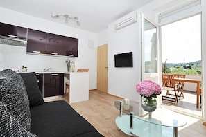 Ein moderner Wohnraum mit Küche, Essbereich und einem Balkon mit Aussicht.