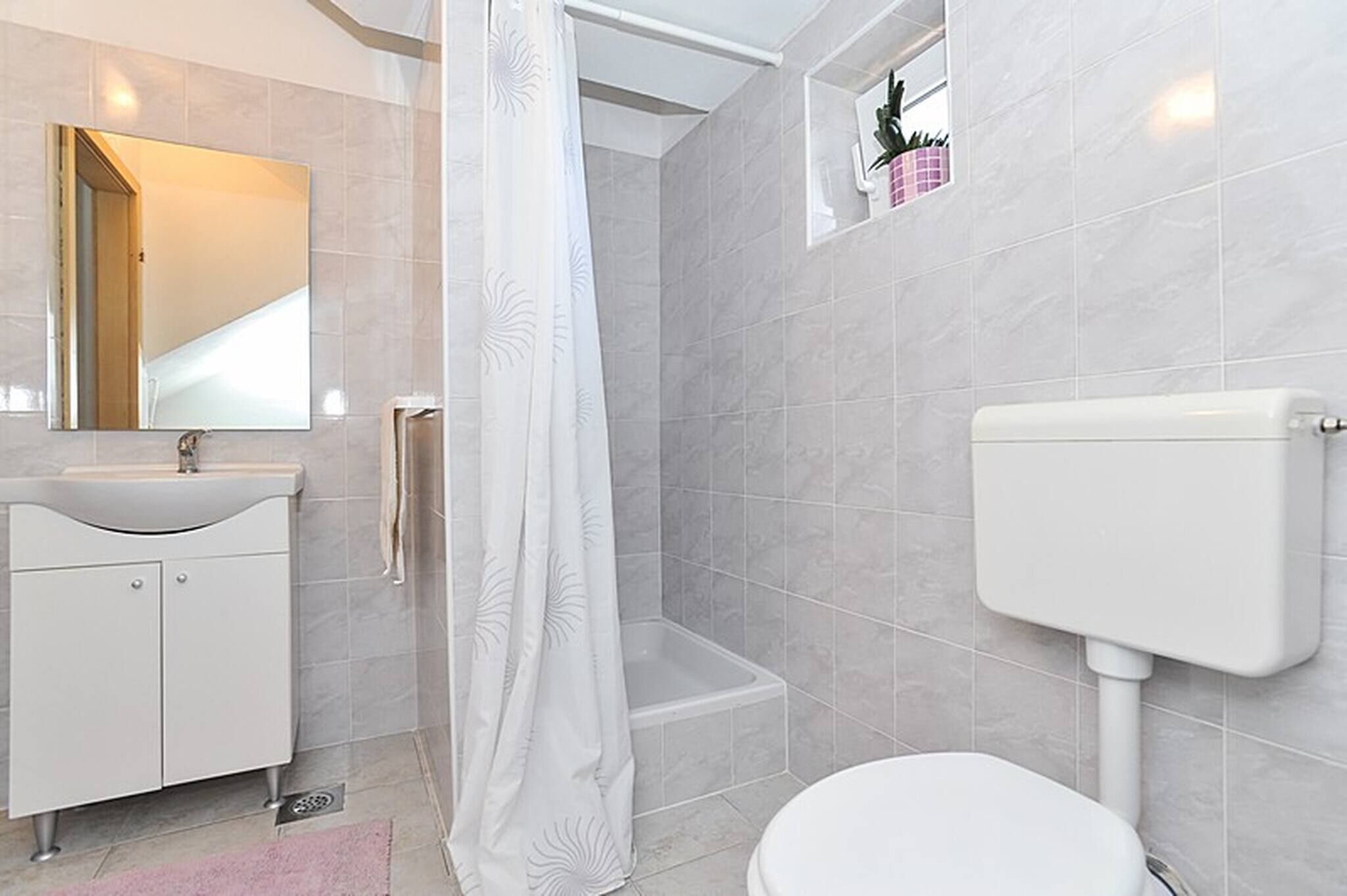 Un baño con ducha, inodoro, lavamanos y espejo.