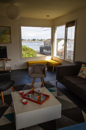 Ein Wohnzimmer mit Blick auf das Meer, inklusive Sofa, Couchtisch mit Tablett und einer Bank.
