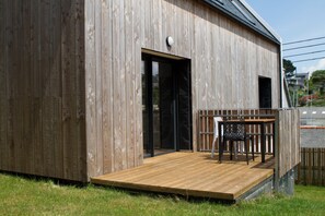 Ein Holzhaus mit einer Terrasse, einer Tür und einem Fenster.