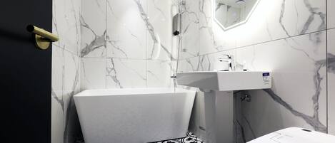 A bathroom with a white bathtub, a sink, and a toilet.