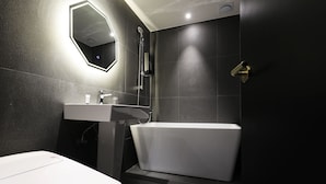 A modern bathroom with a white bathtub, a sink, and a mirror. - Stay25 (Seongnam)