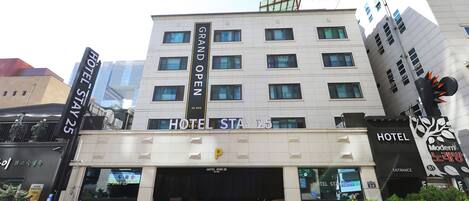 Un hotel con un letrero que dice 'HOTEL STAY 25' y 'GRAN APERTURA'.