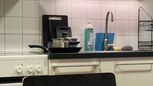 Una cocina con armarios blancos, estufa, lavabo y un comedor con una mesa lista para dos.