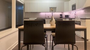 Una cocina moderna con armarios blancos, una mesa de comedor con sillas y un jarrón con una planta.