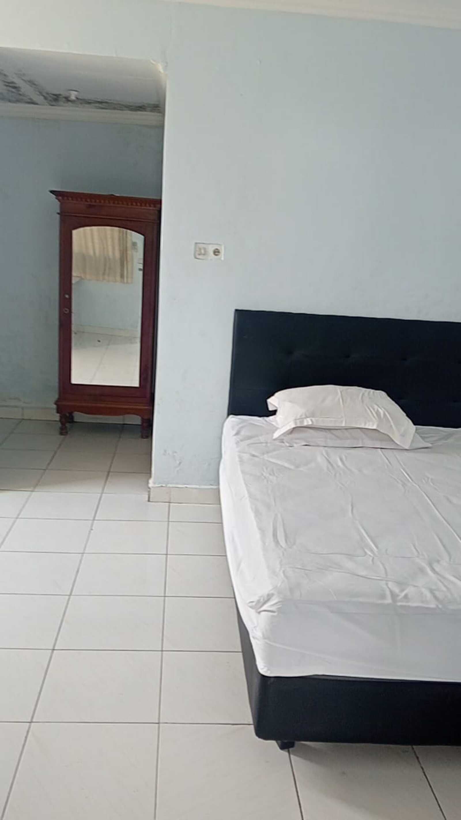 Un dormitorio con una cama, un armario de madera y un espejo.